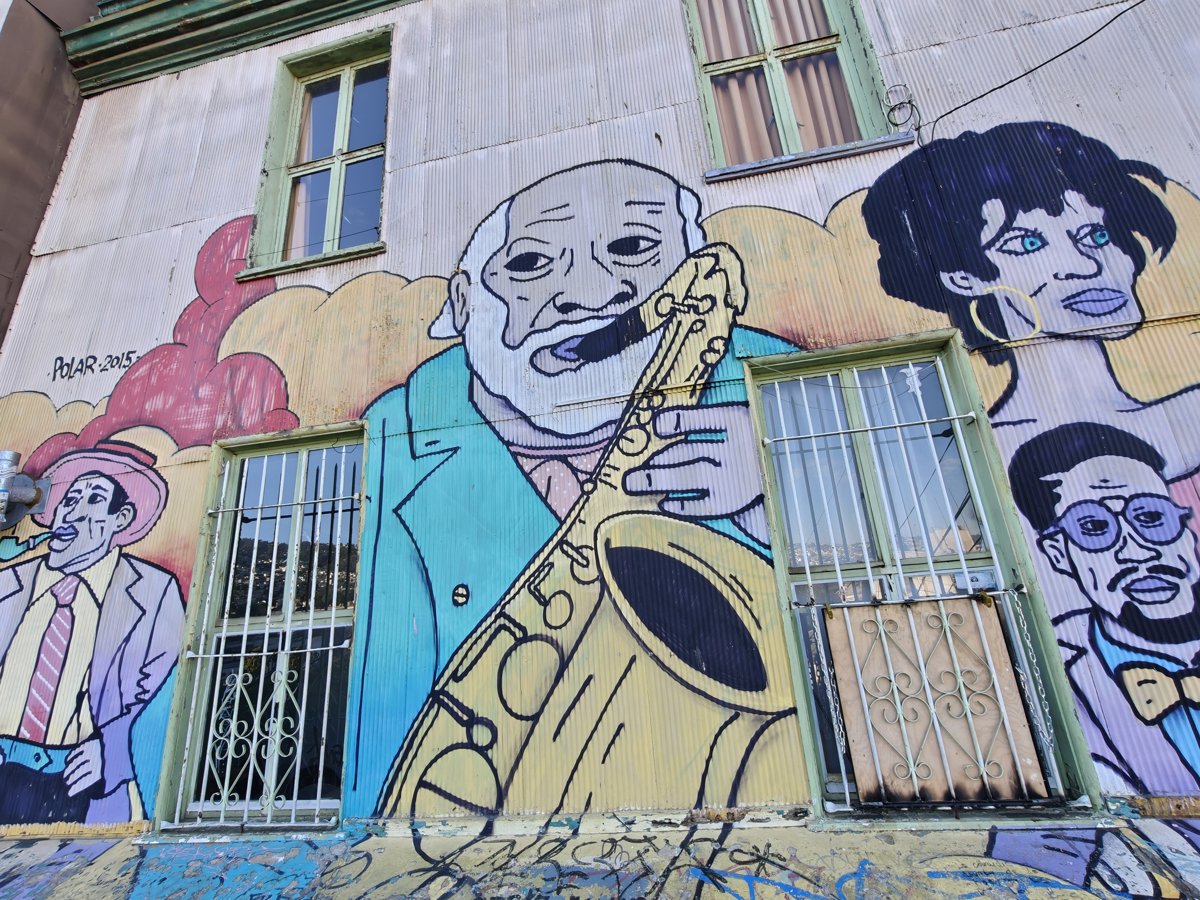 Mural of a saxophone player and other faces on a building in Valparaiso