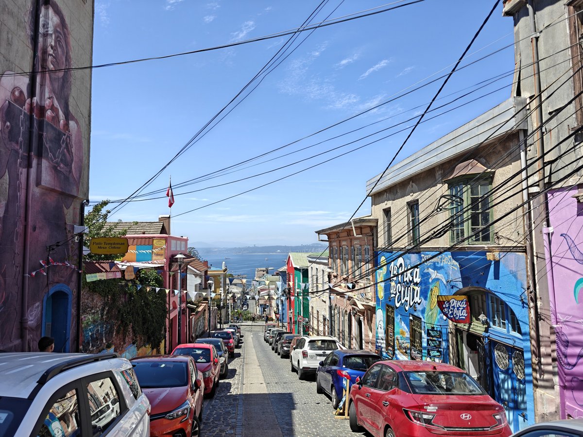 Steep Valparaiso street lined with colourful houses and a view of the sea